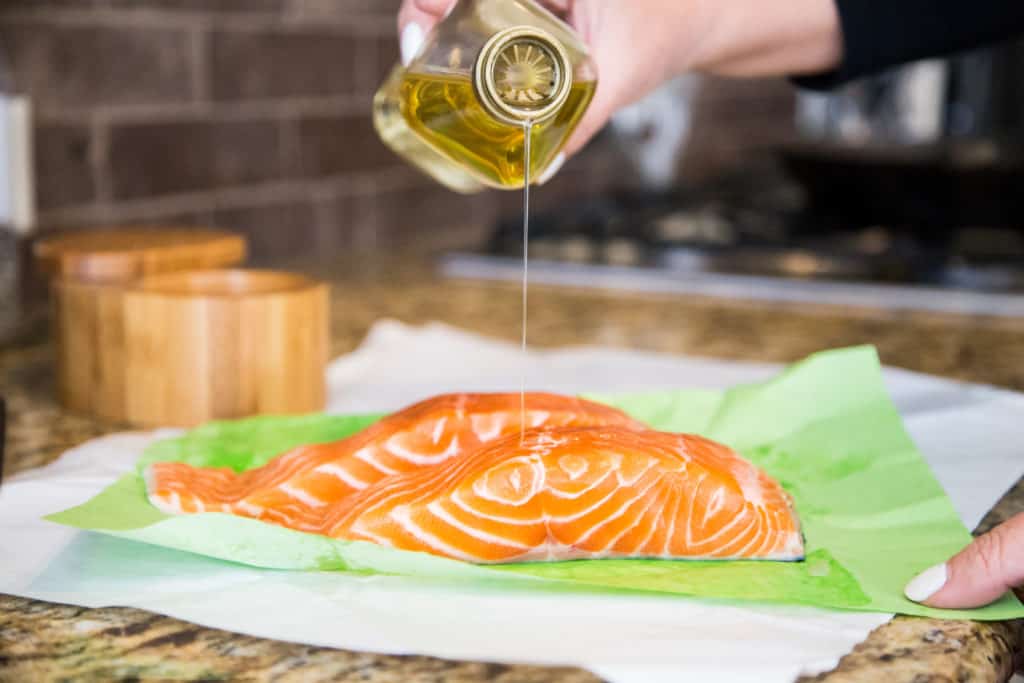 drizzling olive oil onto a piece of salmon