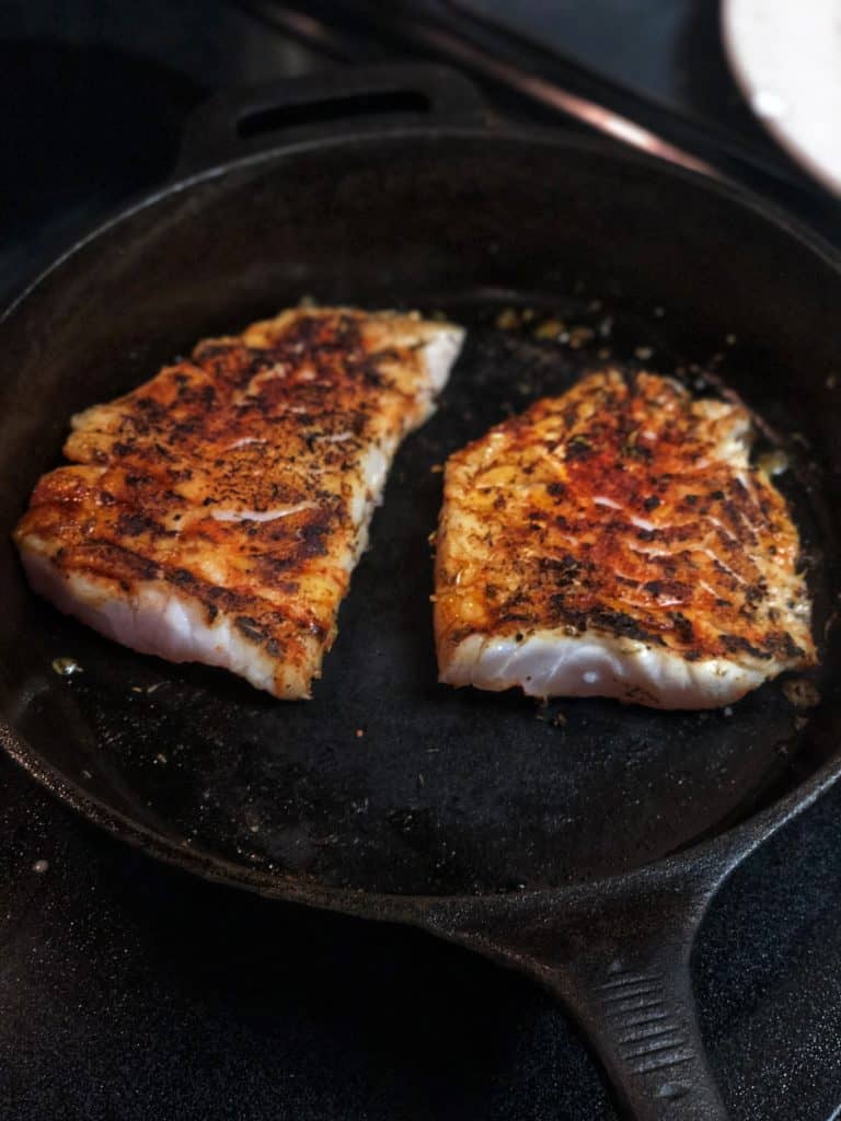 two filets of blackened grouper in a cast iron pan