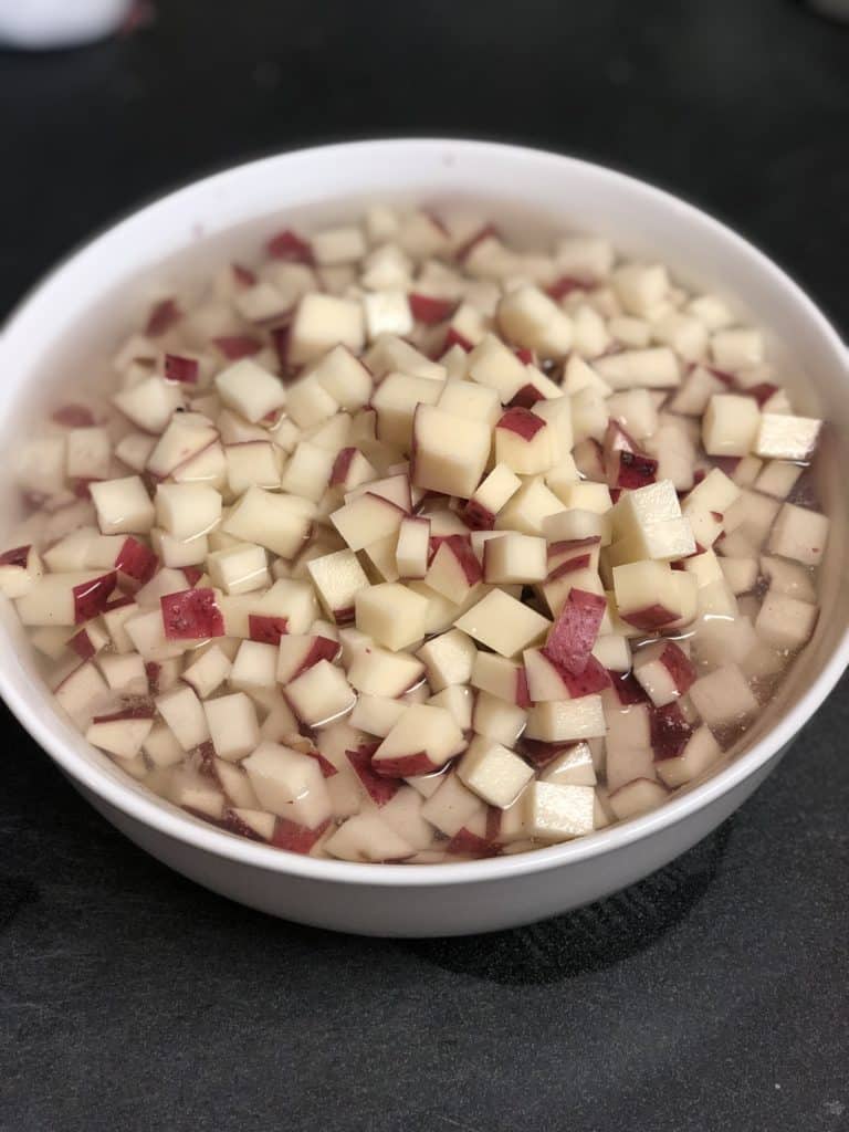 a white bowl of diced potatoes