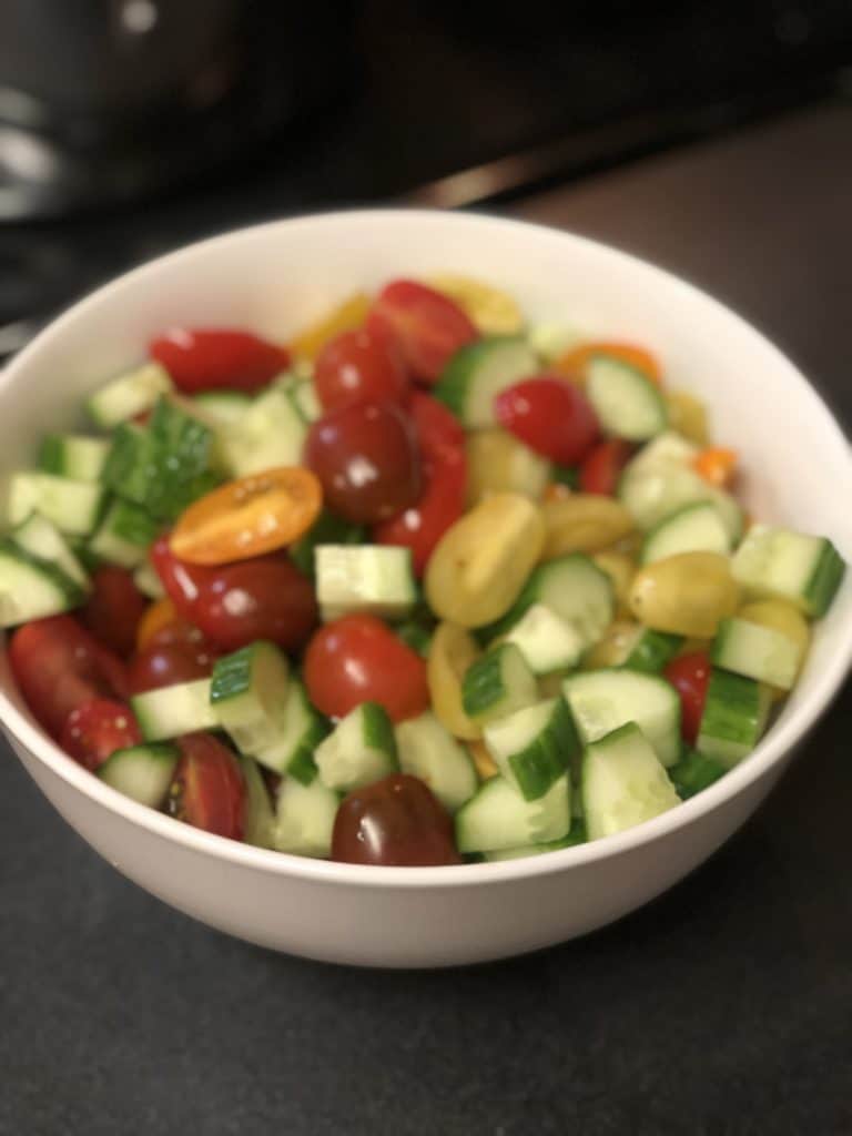 a white bowl of veggies for a salad