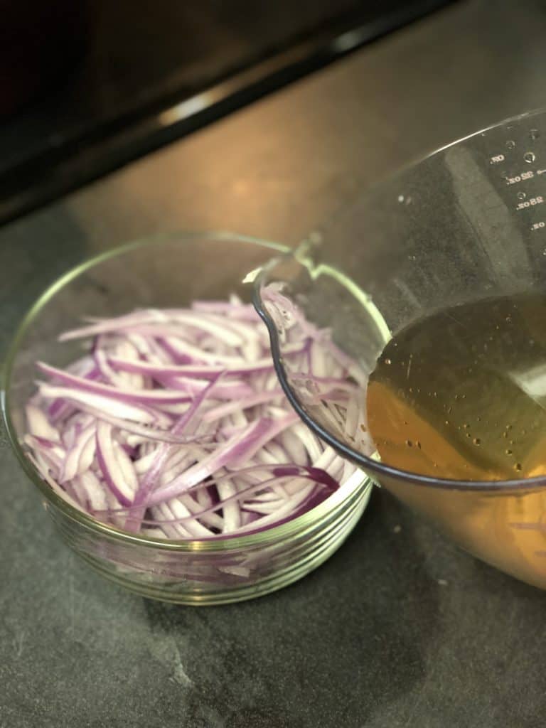 a glass bowl of red onions