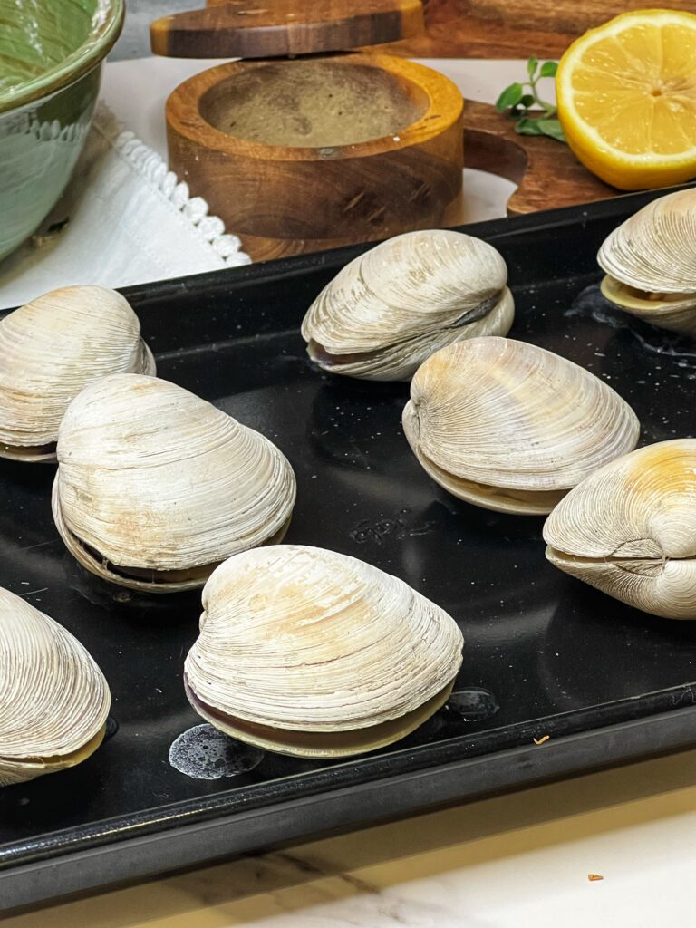 Slightly opened clams on a baking sheet.