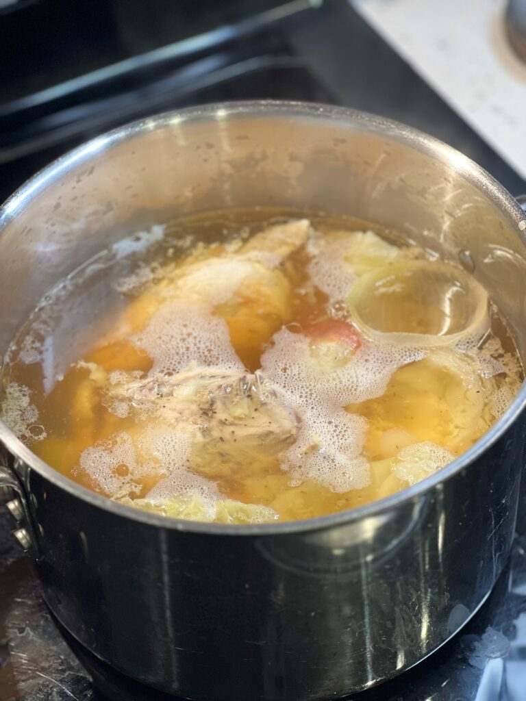 A pot of cooked vegetables and chicken in broth.