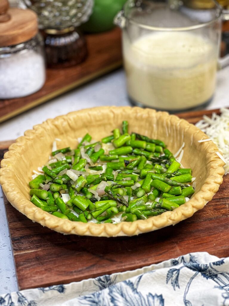 A frozen, deep dish pie crust filled with a layer of cheese and a mixture of sautéed asparagus and shallots.