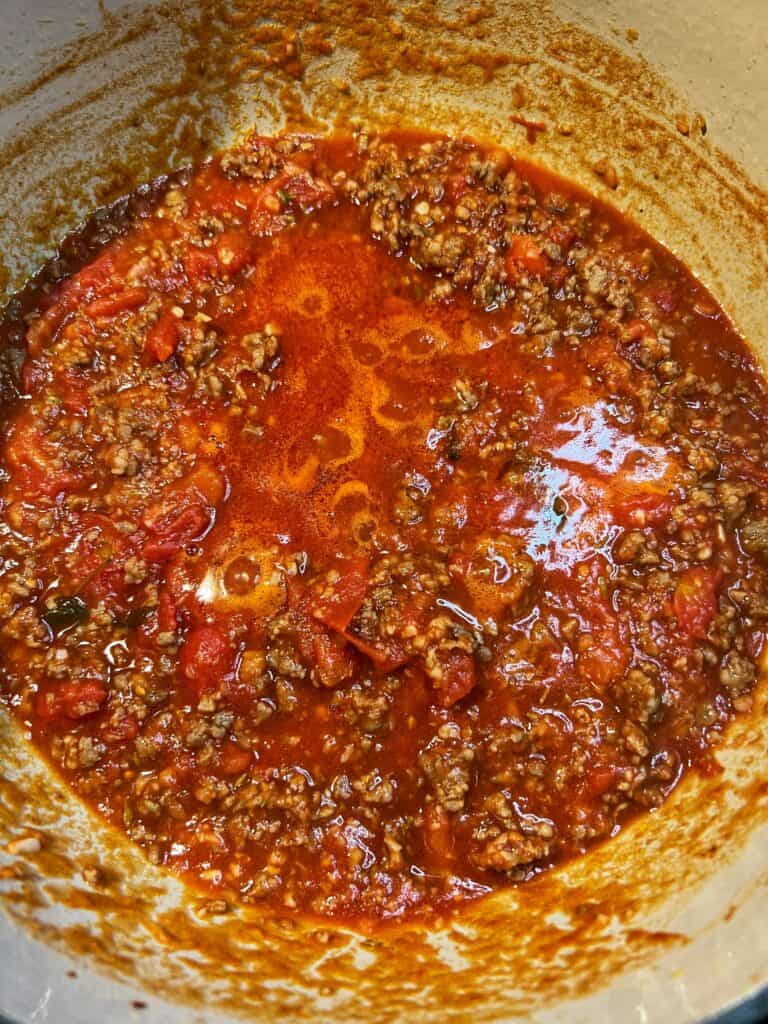 A pot of spicy sausage tomato sauce simmering in a large pot.