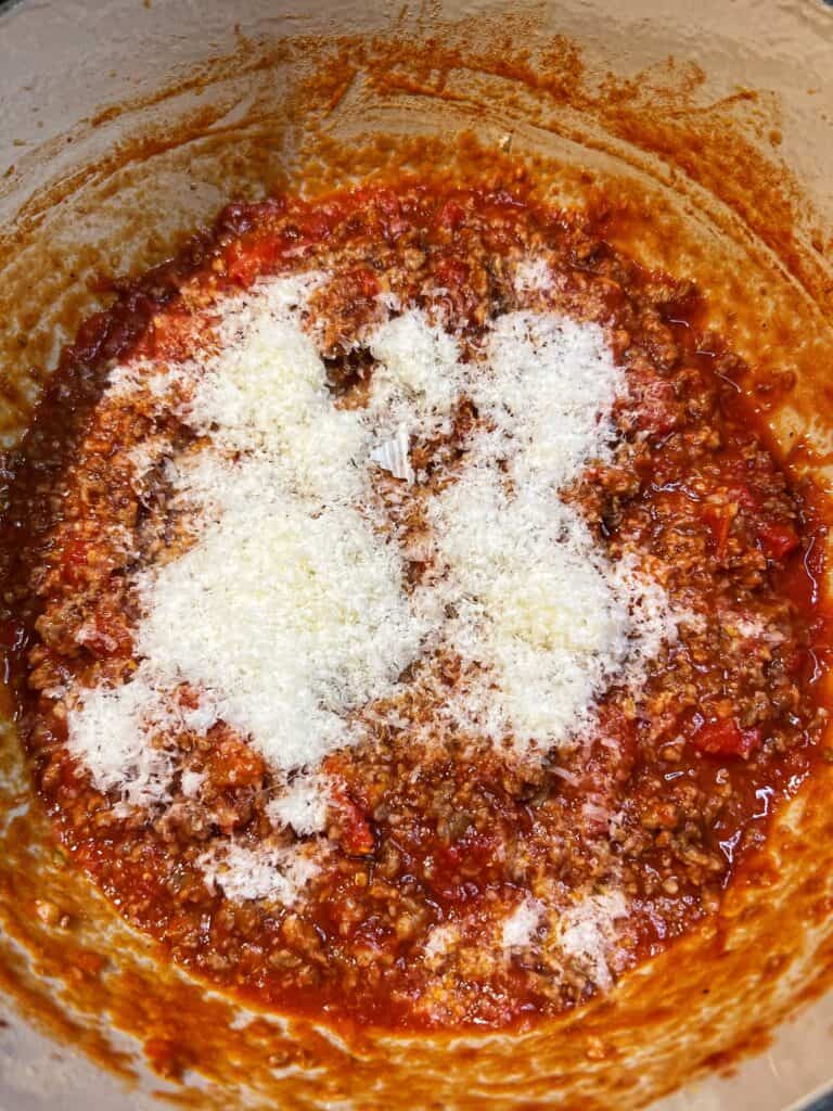 Freshly grated Parmesan cheese added to a pot of Spicy Sauce Tomato Sauce.