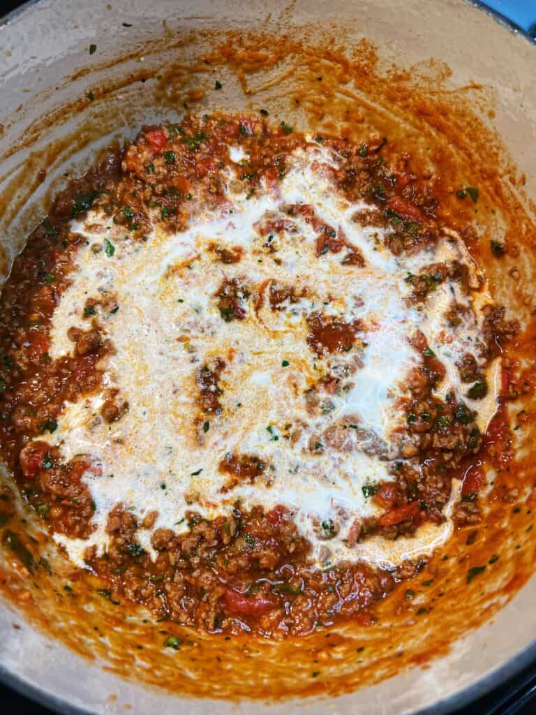 Heavy cream added to a pot of spicy sauce tomato sauce.