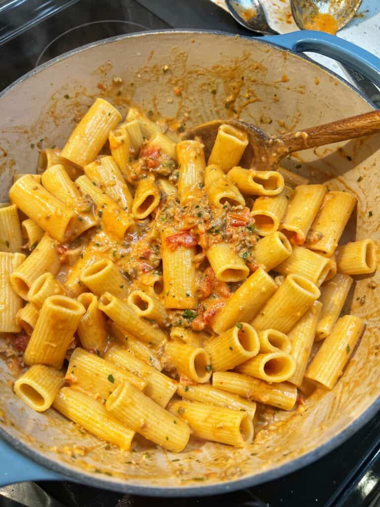 A pot of rigatoni covered in a creamy tomato sauce.