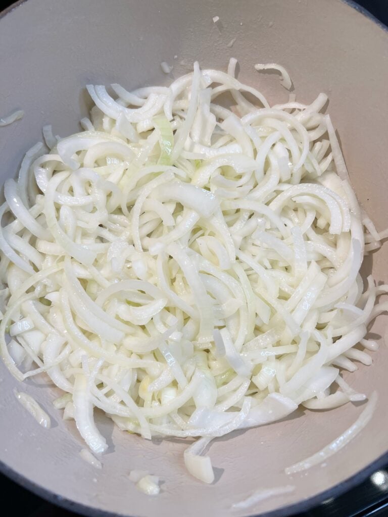 Half-moon sliced yellow onions in a large pot with butter for French Onion Soup.