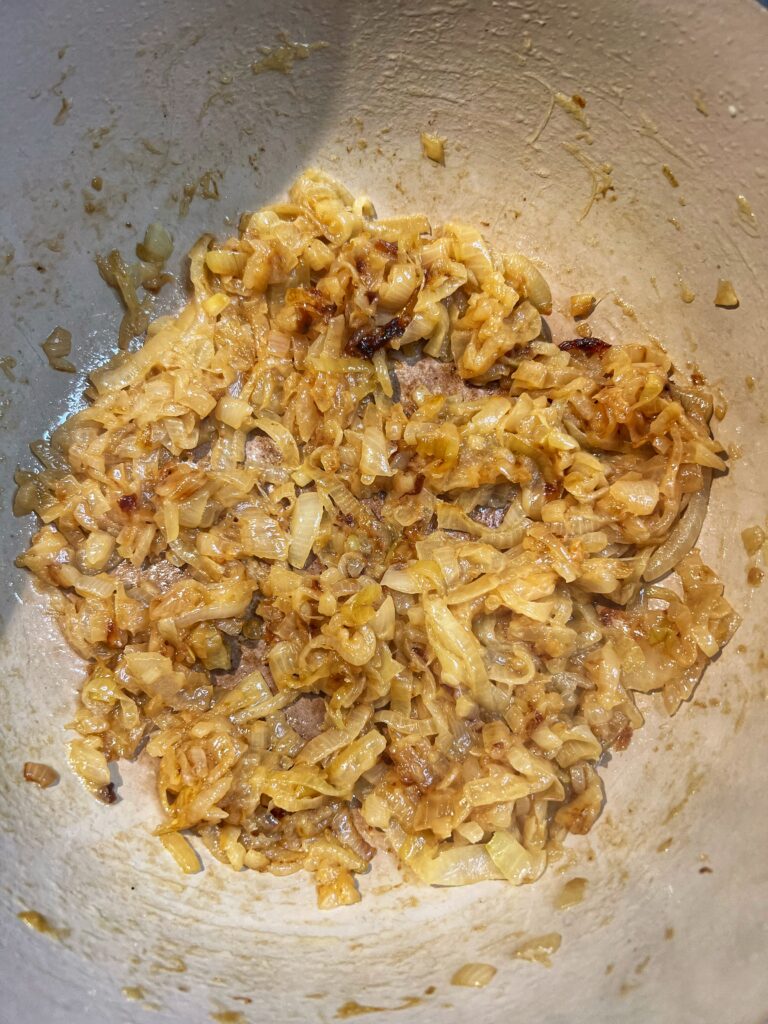 A pot of caramelized onions for French Onion soup. The onions have a brown hue.