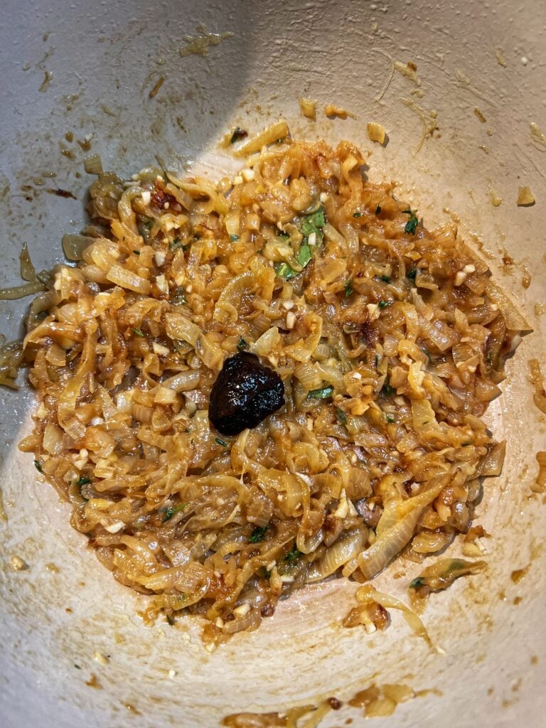 Caramelized onions in a pot with fresh thyme, minced garlic, bay leaves and beef base.