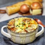 A crock of French onion soup with the top layer of cheese browned.
