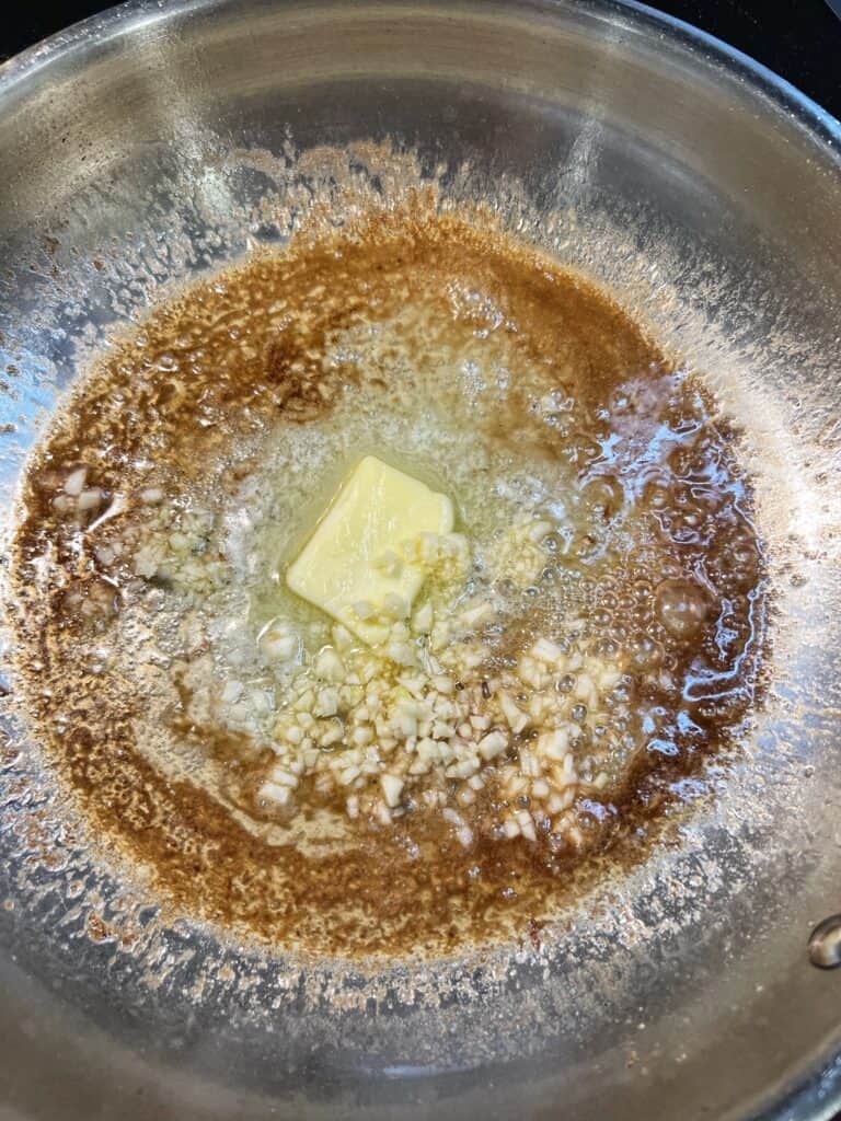 Butter and minced garlic sautéing in a stainless steel pan.