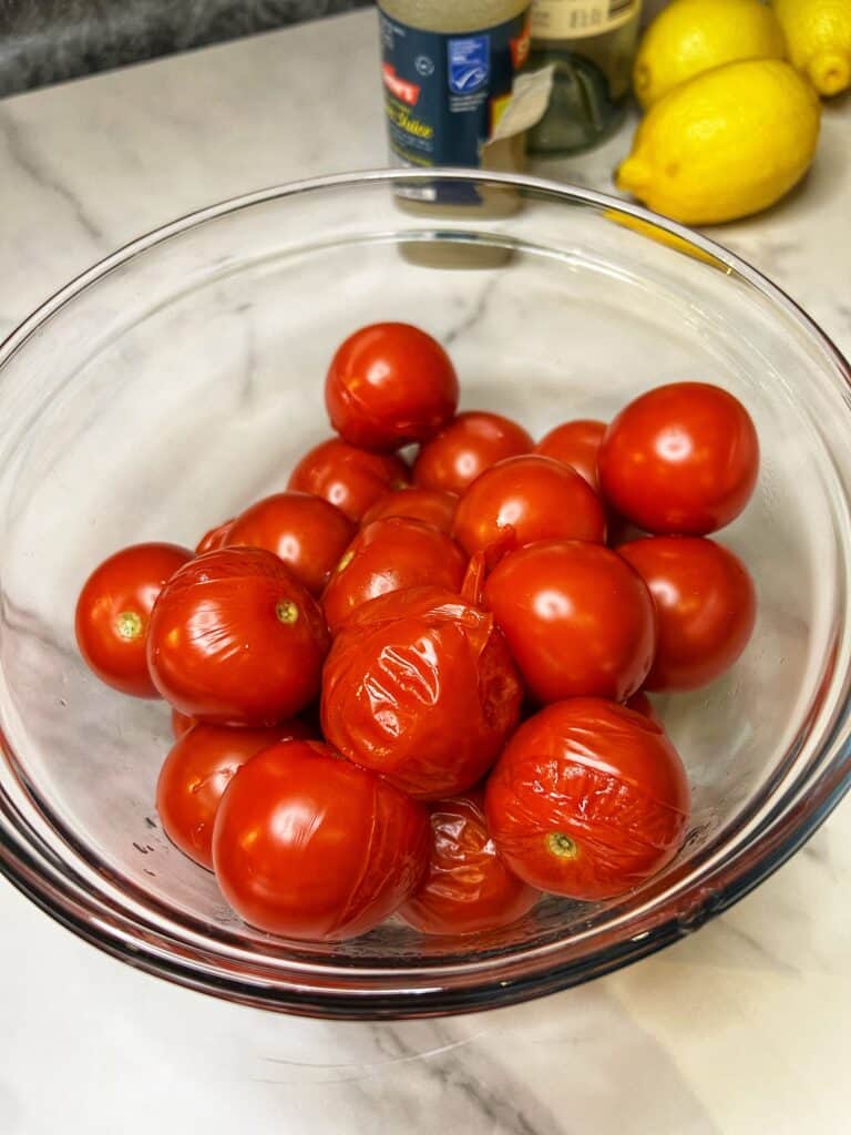 Blanched tomatoes in a glass bowl.