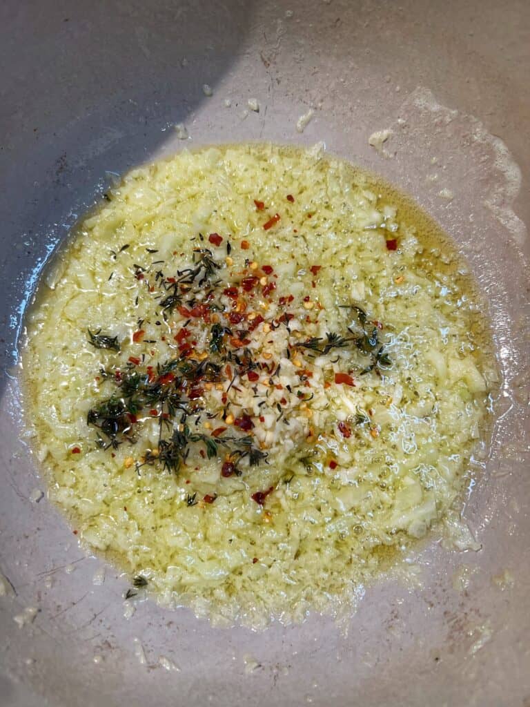 Sautéed onions and fennel in a pot with fresh thyme, minced garlic and crushed red pepper for Classic Homemade Cioppino.