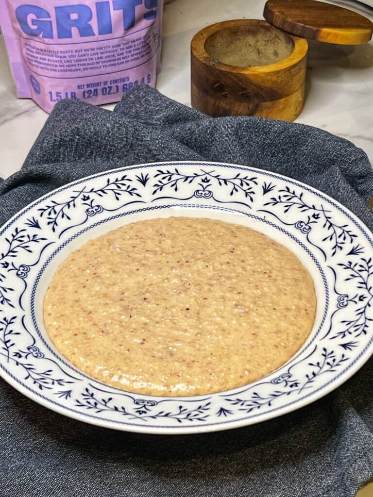 A white bowl with an edge of blue decorative design filled with cooked unicorn grits.