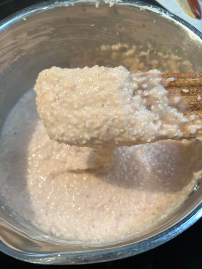 A wooden spatula covered in cooked grits.