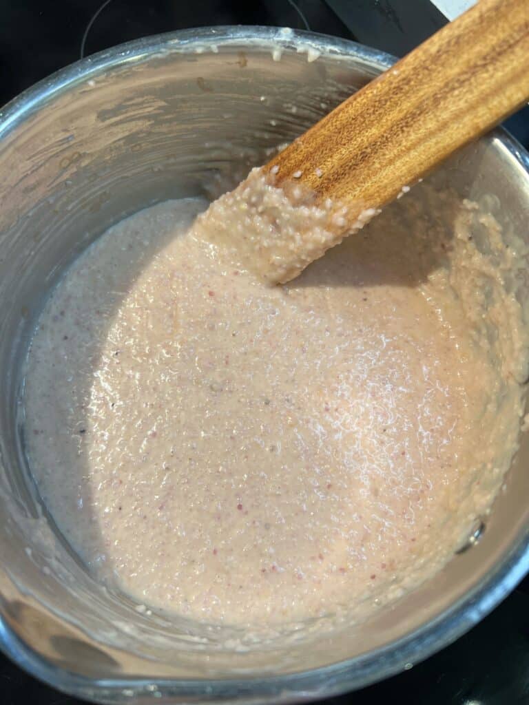 A stainless steel pot of cooked grits.