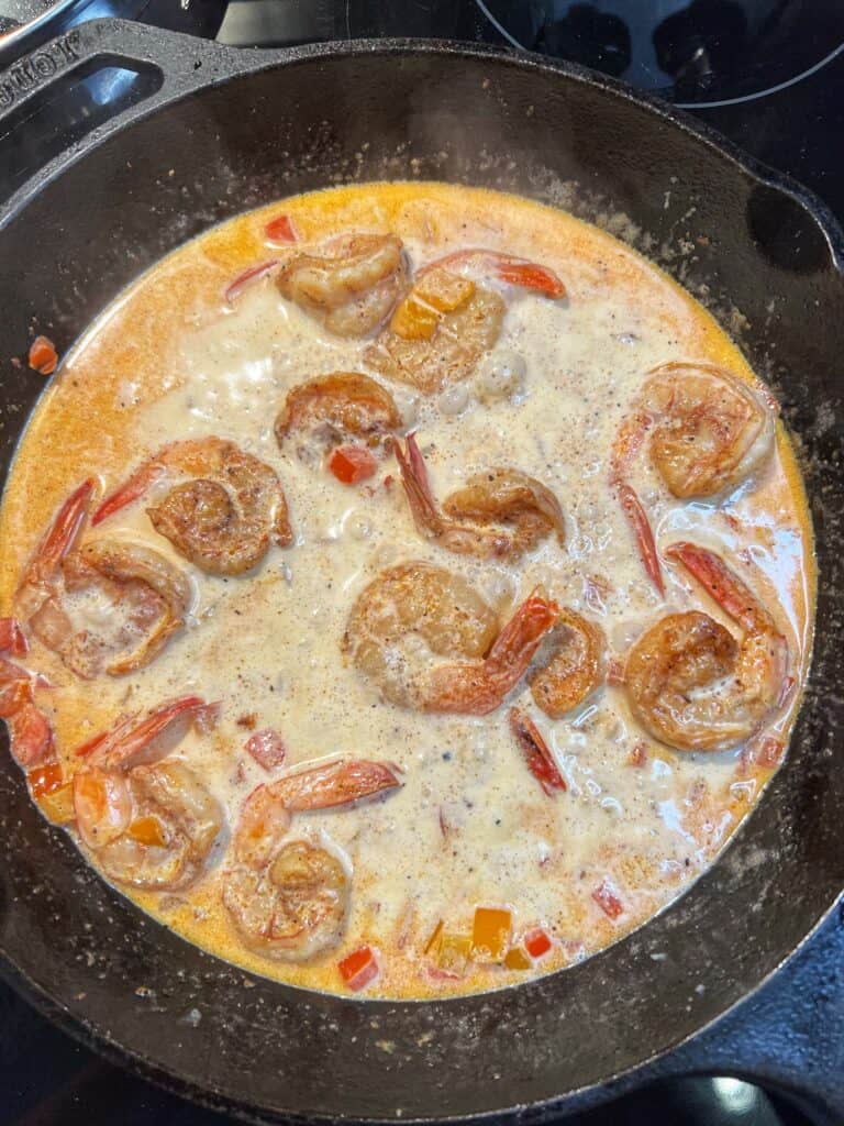 A shrimp and cream sauce simmering in a cast iron pan.