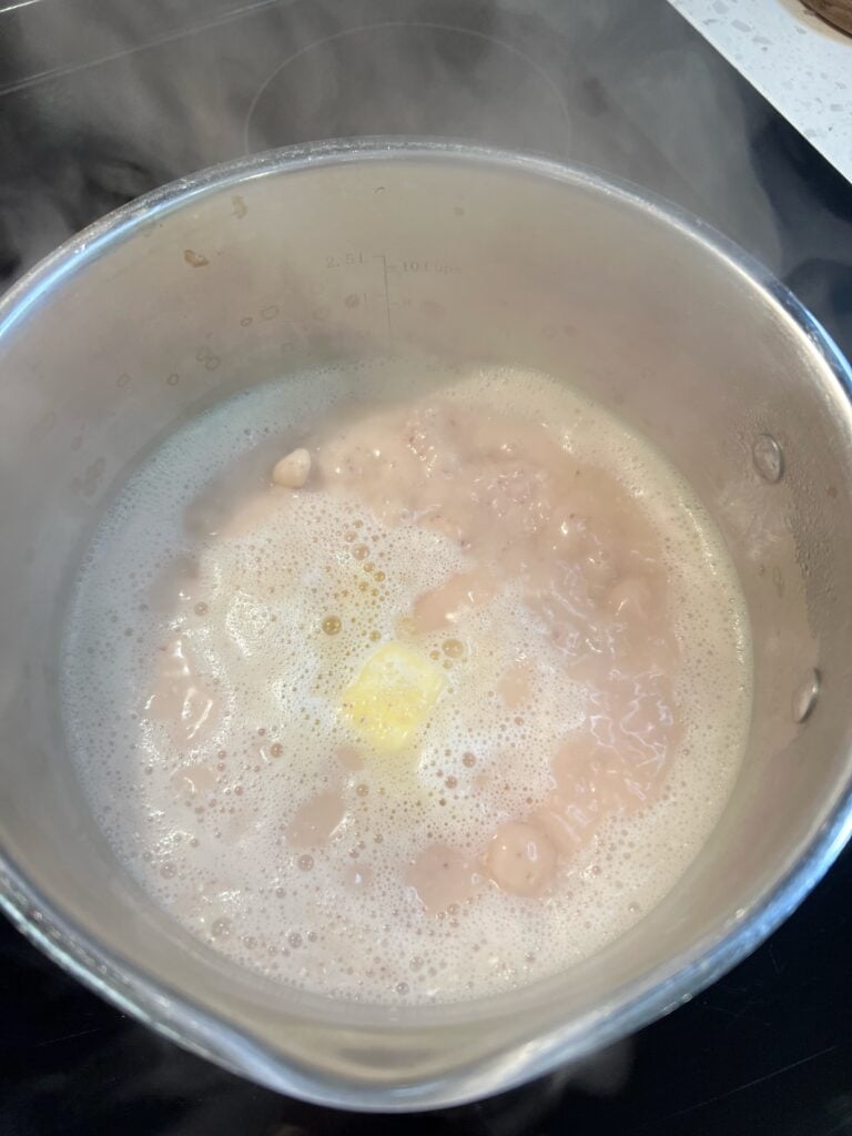 A stainless steel pot of grits simmering.