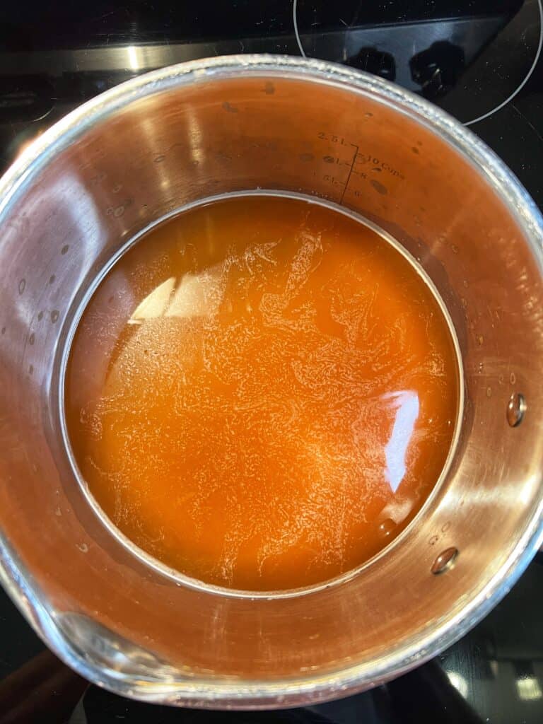 A stainless steel pot filled with chicken broth.