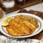 A piece of pan fried trout with a side of rice pilaf.