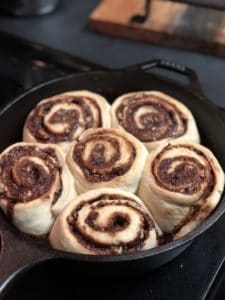 six cinnamon rolls baked in a cast iron pan