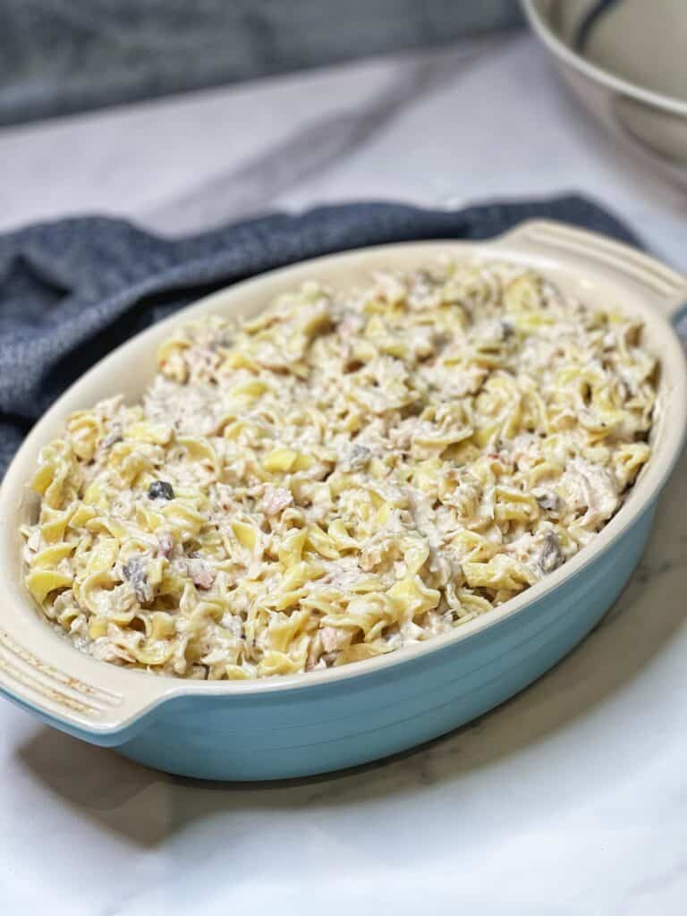 A blue casserole dish filled with a tuna noodle mixture.