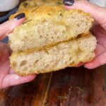Me holding two cut pieces of focaccia, one on top of the other. I am showing the inside of each piece.