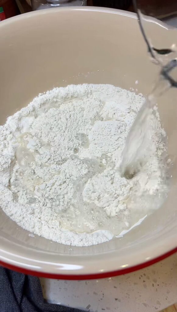 Pouring water in a bowl with flour.