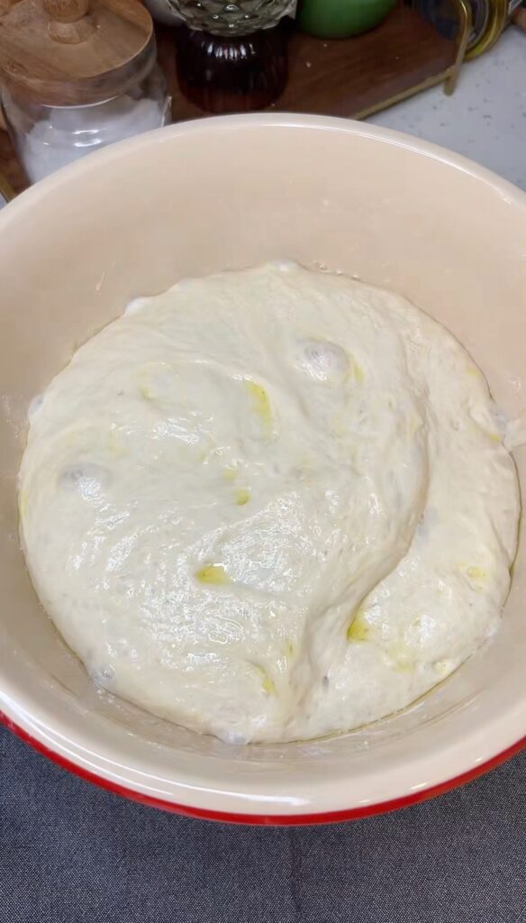 A ball of focaccia dough that has doubled in size in a bowl.