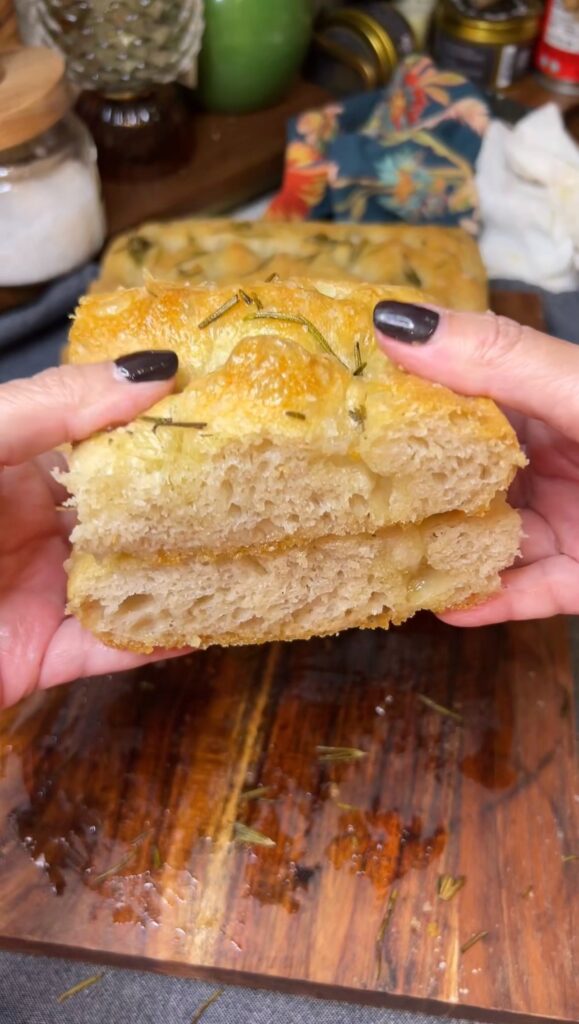Me holding two pieces of same day focaccia, one on top of the other, showing the inside