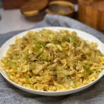 A white bowl filled with Haluski Cabbage and Noodles. The slightly browned, shredded cabbage is mixed with cooked egg noodles.