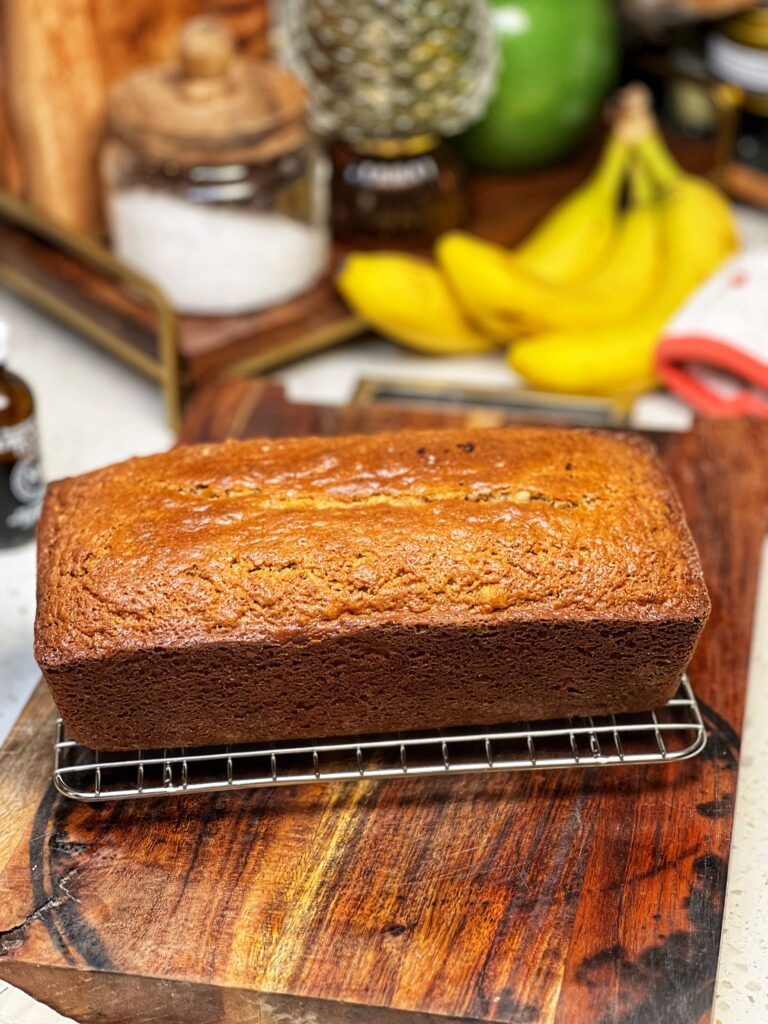 A loaf of banana nut bread sitting on a wire rack.