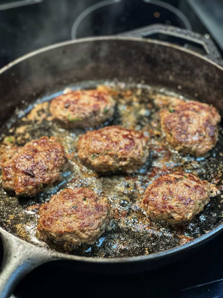 Seared beef patties in a cast iron pan.