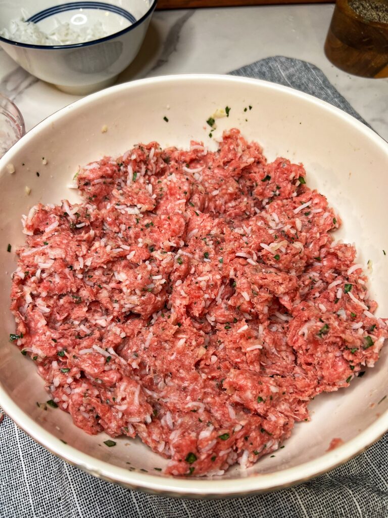 The ground beef mixture for cabbage rolls (halupki) in a white bowl.