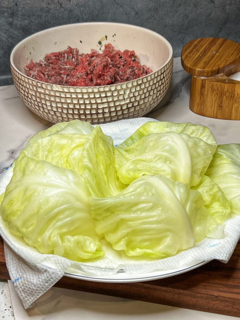 A paper towel lined plate filled with steamed green cabbage leaves.