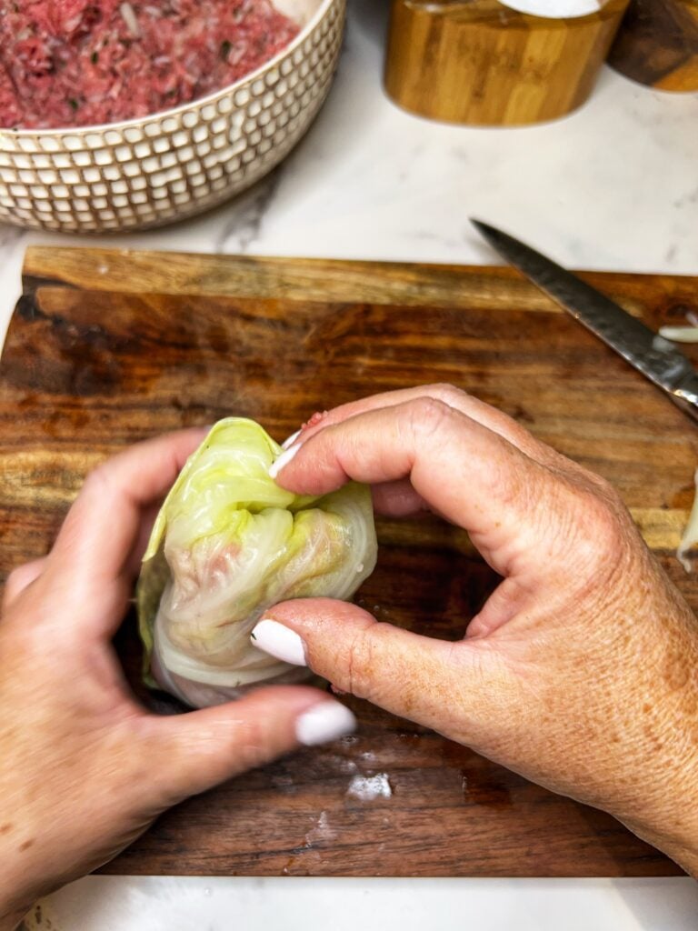Tucking the corners of a filled cabbage leaf into the center.
