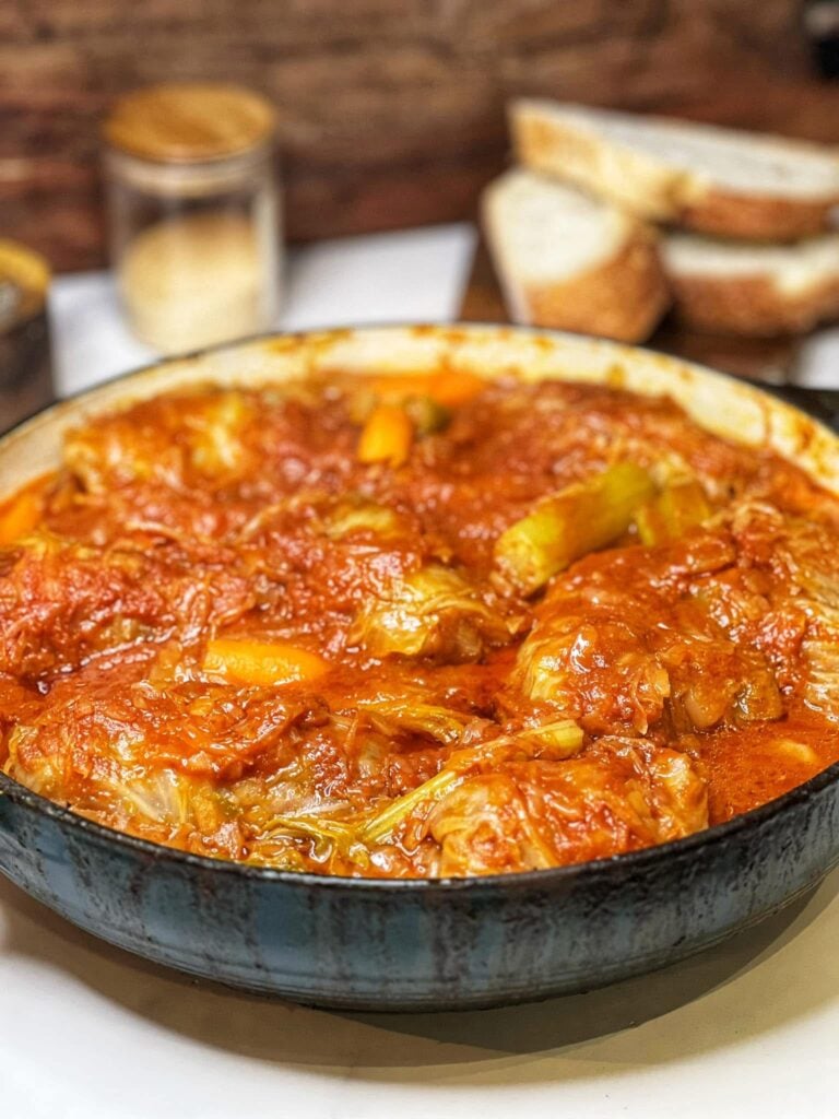 A blue enameled cast iron pan filled with cooked cabbage rolls (halupki).