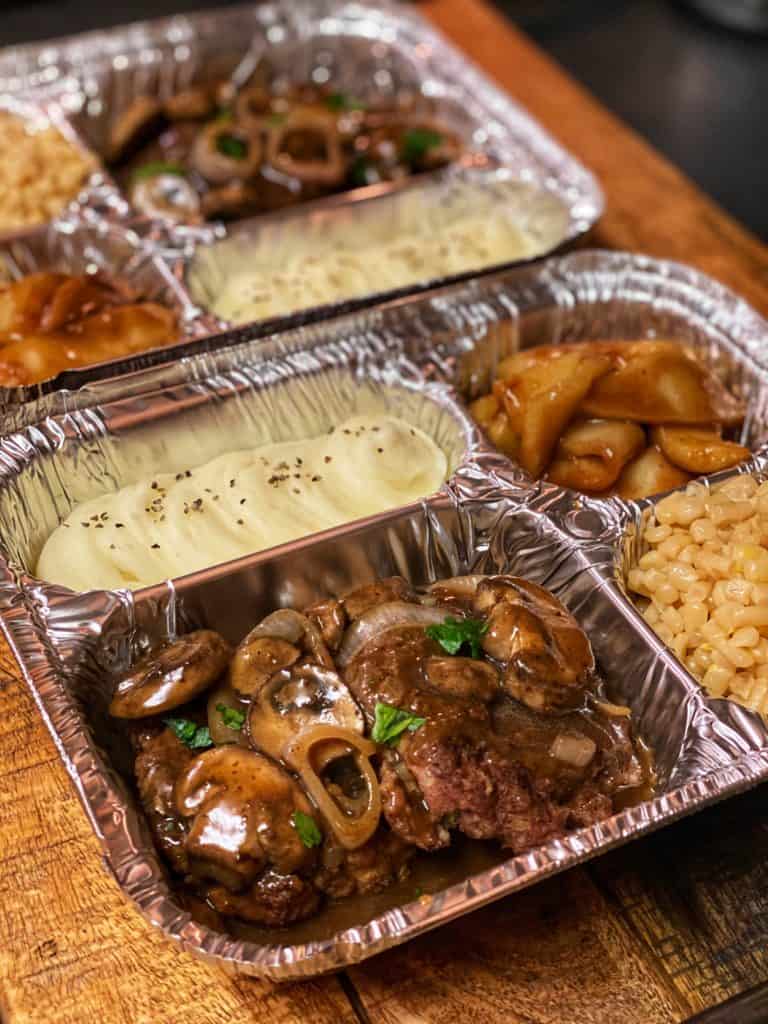 TV dinner with Salisbury Steak, fried apple slices, mashed potatoes and corn.