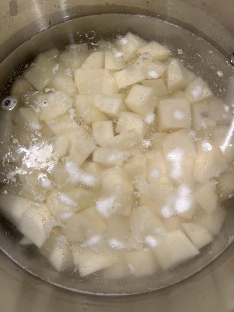 A pot of peeled and chunked potatoes in water ready to boil.