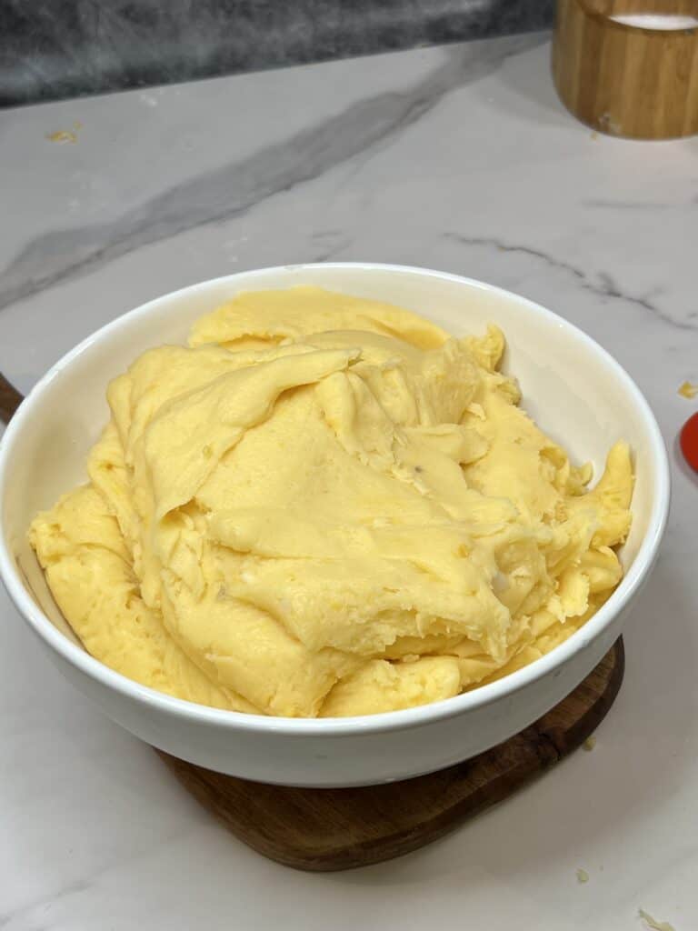A white bowl filled with potato/cheese filling for pierogies.