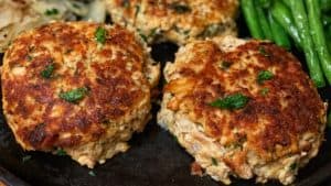 a plate of salmon patties with fried potatoes and green beans