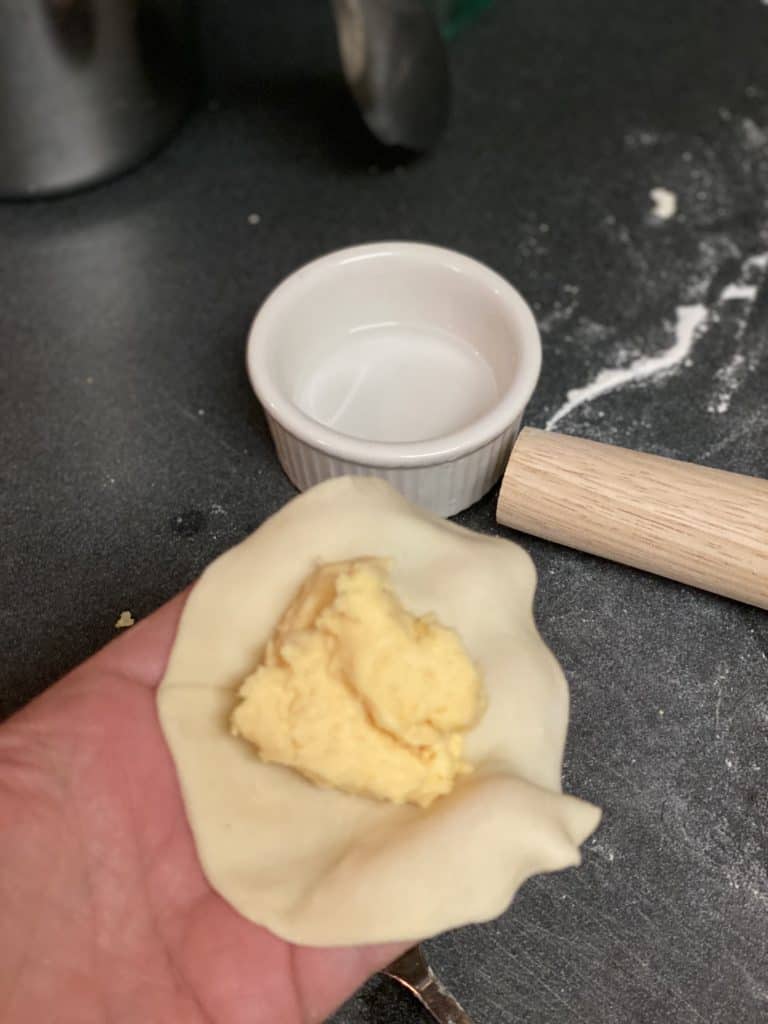 Filling and sealing dough with water for pierogies.