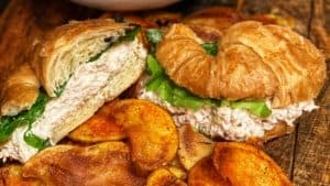a chicken salad croissant with a side of cajun chips