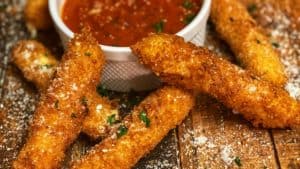 fried mozzarella cheese sticks on a wooden board