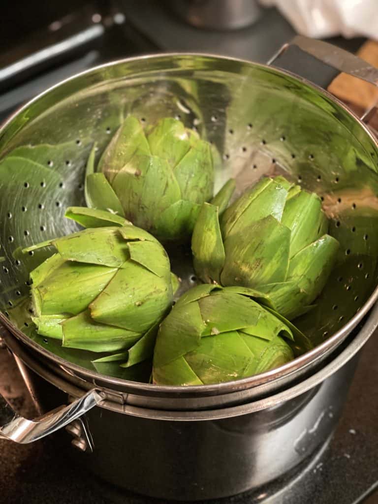 artichoke halves in metal colander