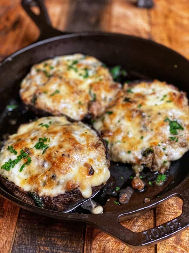 three stuffed portabella mushrooms in a cast iron pan
