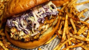 two blackened grouper sandwich with shoestring french fries on newspaper