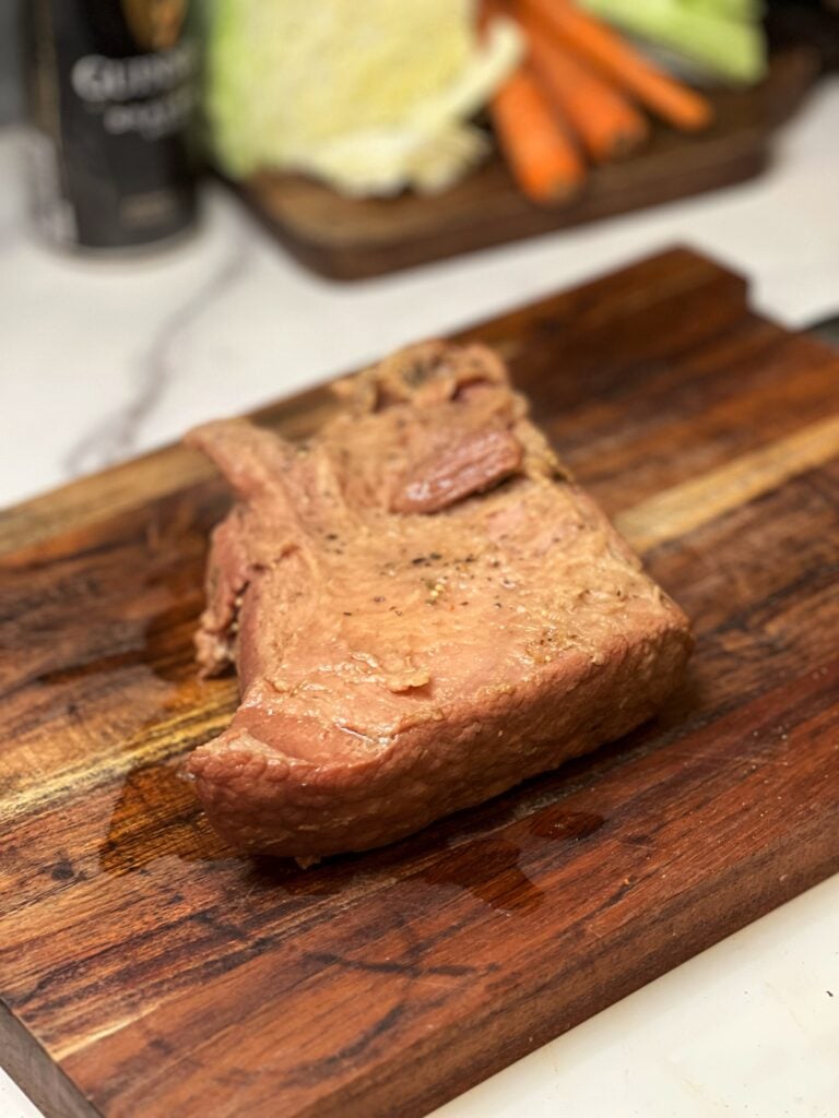 A piece of slow cooked corned beef resting on a wooden cutting board 